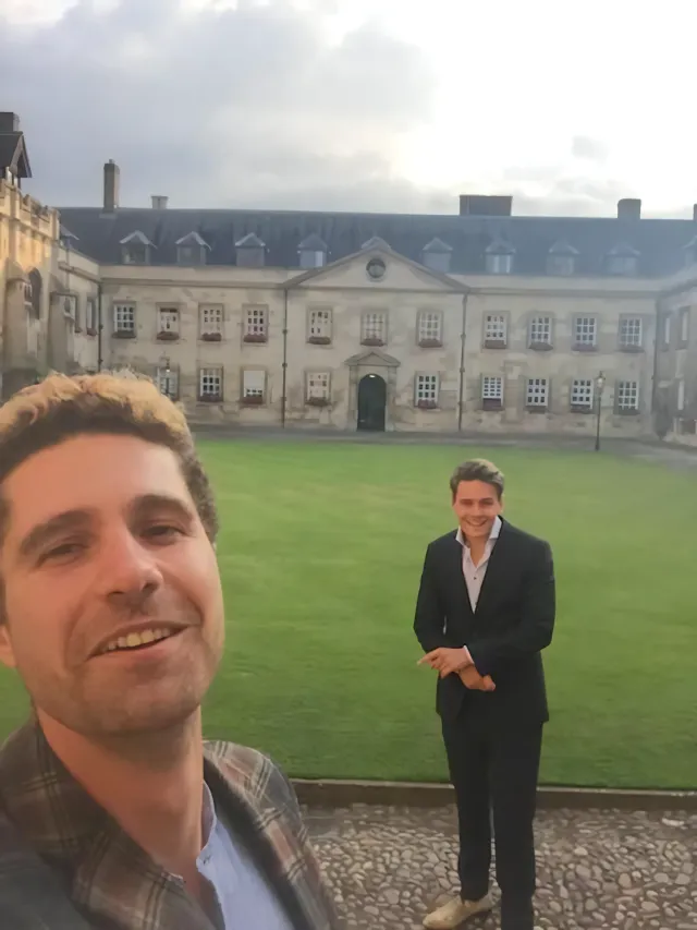 Two people, Max Bautista Perpinya and Martijn van der Meer, standing in front of a fancy building on the campus of Cambridge